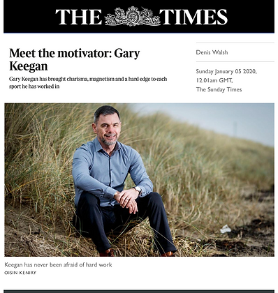 Man sitting on grass in a field wearing a blue shirt, featured in The Times' Meet the Motivator article.