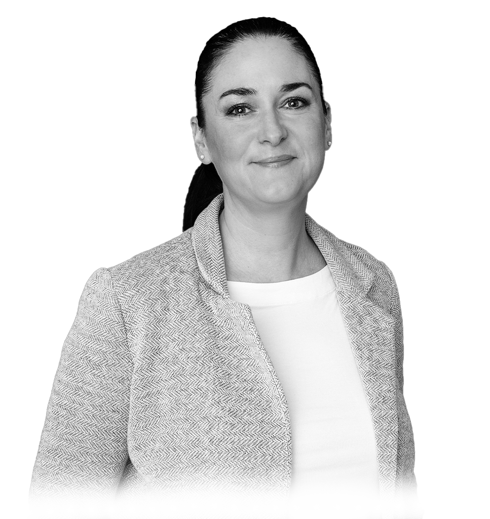 Portrait of a smiling woman in a smart blazer against a plain background.